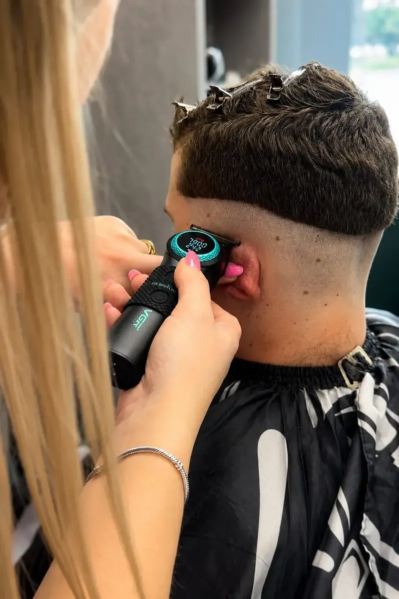 Precyzyjne wykańczanie skin fade maszynką przy linii ucha i karku