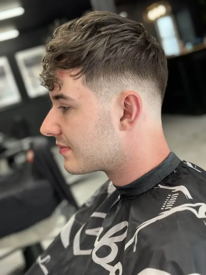Męskie strzyżenie textured fringe z naturalną teksturą na górze i mid fade po bokach